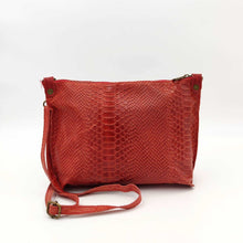 Cargar imagen en el visor de la galería, Bolso bandolera piel vacuno, efecto escamas, de tamaño mediano, cierra con cremallera, de LaNievina. Color rojo mate, por detrásBolso bandolera en piel vacuno, efecto escamas Cuadro pequeño de piel negra cosido como adorno en un de los frontales. Correa de 110 cm. ajustable, en piel del mismo color, con anillas y ganchos en latón envejecido. Interior forrado en tela color negro, con bolsillo cerrado con cremallera. De LaNievina. Color rojo mate, vista trasera