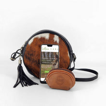 Cargar imagen en el visor de la galería, Bolso bandolera redondo de pelo y pielBolso bandolera de forma redonda. Delantera de pelo, trasera de piel negra, con bolsillo cerrado con cremallera. Cierra con cremallera. Correa ajustable (no desmontable) de 120cm. Fornituras plateadas. Pompón de adorno con flecos de piel. Forrado interior en tela, con un bolsillo cerrado con cremallera, de LaNievina. Color potro, vista con contenido para referencia de tamaño
