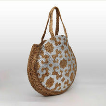 Cargar imagen en el visor de la galería, Bolso de yute redondo, con dibujos tipo étnico en color plateado. Cierra con clip imantado. Ideal para piscina o playa por su gran capacidad. Doble asa para hombro. No forrado. Yute 100%, de LaNievina. Vista lateral