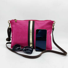 Cargar imagen en el visor de la galería, Bandolera de piel lisa color fucsia de LaNievina, cierra con cremallera y lleva una franja central decorativa en negro y oro. Vista frontal con contenido para referencia de medidas