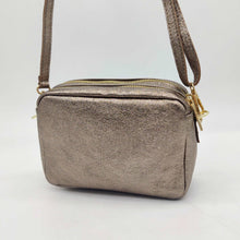 Cargar imagen en el visor de la galería, Bolso bandolera de piel efecto metalizado color bronce de LaNievina. Doble compartimento para llevar todo bien organizado. Asa ajustable. Forrado interior. Cierra con cremallera.Vista colgado