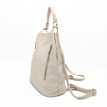 Cargar imagen en el visor de la galería, Mochila de piel lisa. Asa corta para llevar en la mano o brazo, y tirantes ajustables para llevar como mochila. Dos bolsillos delanteros cerrados con cremallera, para llevar a mano las cosas más imprescindibles. Gran capacidad. Muy segura, pues cierra con cremallera por la parte trasera. Interior forrado textil, con bolsillo cerrado con cremallera.La Nievina. Color hueso, vista lateral