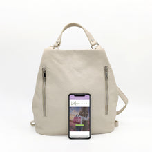 Cargar imagen en el visor de la galería, Mochila de piel lisa. Asa corta para llevar en la mano o brazo, y tirantes ajustables para llevar como mochila. Dos bolsillos delanteros cerrados con cremallera, para llevar a mano las cosas más imprescindibles. Gran capacidad. Muy segura, pues cierra con cremallera por la parte trasera. Interior forrado textil, con bolsillo cerrado con cremallera.La Nievina. Color hueso. Vista frontal.