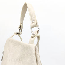 Cargar imagen en el visor de la galería, Mochila de piel lisa. Asa corta para llevar en la mano o brazo, y tirantes ajustables para llevar como mochila. Dos bolsillos delanteros cerrados con cremallera, para llevar a mano las cosas más imprescindibles. Gran capacidad. Muy segura, pues cierra con cremallera por la parte trasera. Interior forrado textil, con bolsillo cerrado con cremallera.La Nievina. Color hueso, detalle del asa