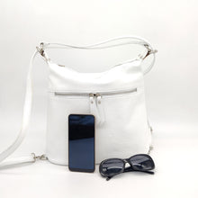 Cargar imagen en el visor de la galería, Mochila de piel de color blanco. Asa para llevar al hombro y tirantes para llevar como mochila. Cierra con cremallera. Bolsillo frontal y bolsillo trasero, ambos cerrados con cremallera. Anillas y detalles metálicos plateados. Interior forrado textil, con bolsillo cerrado con cremallera. Gran capacidad. LaNievina. Vista con contenido para referencias