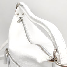 Cargar imagen en el visor de la galería, Mochila de piel de color blanco. Asa para llevar al hombro y tirantes para llevar como mochila. Cierra con cremallera. Bolsillo frontal y bolsillo trasero, ambos cerrados con cremallera. Anillas y detalles metálicos plateados. Interior forrado textil, con bolsillo cerrado con cremallera. Gran capacidad. LaNievina. VIsta del cierre