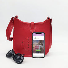 Cargar imagen en el visor de la galería, Bolso de piel color rojo. Puntitos taladrados en el frontal a modo de adorno. Cierra con una tira con clip imantado y cremallera. Asa larga para llevar al hombro. La Nievina Frontal con contenido para referencia de tamaño