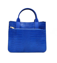 Cargar imagen en el visor de la galerÃa, Bolso de mano de piel efecto escamas azul cobalto de LaNievina. Tiene dos asas cortas con bolsillo frontal y correa por si quiere llevarse al hombro en algun momento. Interior forrado de piel, con bolsillo interior. Cierre de cremallera. Vista frontal