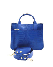 Cargar imagen en el visor de la galerÃa, Bolso de mano piel efecto cocodrilo azul de asas cortas con bolsillo frontal y correaBolso de mano de piel efecto escamas azul cobalto de LaNievina. Tiene dos asas cortas con bolsillo frontal y correa por si quiere llevarse al hombro en algun momento. Interior forrado de piel, con bolsillo interior. Cierre de cremallera. Vista con la asa larga