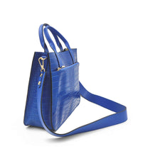 Cargar imagen en el visor de la galerÃa, Bolso de mano de piel efecto escamas azul cobalto de LaNievina. Tiene dos asas cortas con bolsillo frontal y correa por si quiere llevarse al hombro en algun momento. Interior forrado de piel, con bolsillo interior. Cierre de cremallera. Vista con el sas larga colocada