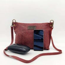 Cargar imagen en el visor de la galería, Bolso bandolera de mujer, piel vacuno, efecto escamas, de tamaño mediano, cierra con cremallera, de LaNievina. Color grisBolso bandolera en piel vacuno, efecto escamas Cuadro pequeño de piel negra cosido como adorno en un de los frontales. Correa de 110 cm. ajustable, en piel del mismo color, con anillas y ganchos en latón envejecido. Interior forrado en tela color negro, con bolsillo cerrado con cremallera. De LaNievina. Color burdeos, frontal con contenido para referencia de tamaño