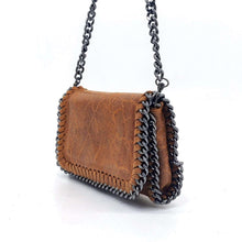 Cargar imagen en el visor de la galería, Bolso de piel de LaNievina, piel aspecto envejecido, con cadenas que adornan los bordes. Cierre clip y cremallera. Llevar cruzado o colgado al hombro, con asa larga de cadena. Color topo. Color camel, vista con asa larga.