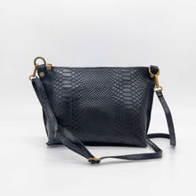 Cargar imagen en el visor de la galería, Bolso bandolera de mujer, piel vacuno, efecto escamas, de tamaño mediano, cierra con cremallera, de LaNievina. Color negro mateBolso bandolera en piel vacuno, efecto escamas Cuadro pequeño de piel negra cosido como adorno en un de los frontales. Correa de 110 cm. ajustable, en piel del mismo color, con anillas y ganchos en latón envejecido. Interior forrado en tela color negro, con bolsillo cerrado con cremallera. De LaNievina. Color negro, v