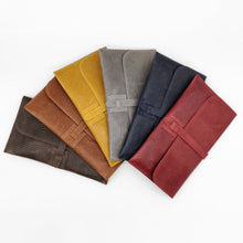 Cargar imagen en el visor de la galería, Cartera clutch en piel rígida. Cierra con solapa y cinta de piel. Dos correas adicionales: una corta para llevarla en la muñeca y otra larga ajustable (aprox. 110 cm.) para poder llevarla también como bandolera si se necesitan las manos libres. Interior en piel, no forrado, con pequeño compartimento plano sin cierre. De LaNievina, gama de colores