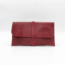 Cargar imagen en el visor de la galería, Cartera clutch en piel rígida. Cierra con solapa y cinta de piel. Dos correas adicionales: una corta para llevarla en la muñeca y otra larga ajustable (aprox. 110 cm.) para poder llevarla también como bandolera si se necesitan las manos libres. Interior en piel, no forrado, con pequeño compartimento plano sin cierre. De LaNievina, color burdeos.