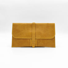 Cargar imagen en el visor de la galería, Cartera clutch en piel rígida. Cierra con solapa y cinta de piel. Dos correas adicionales: una corta para llevarla en la muñeca y otra larga ajustable (aprox. 110 cm.) para poder llevarla también como bandolera si se necesitan las manos libres. Interior en piel, no forrado, con pequeño compartimento plano sin cierre. De LaNievina, color mostaza.