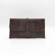 Cargar imagen en el visor de la galería, Cartera clutch en piel rígida. Cierra con solapa y cinta de piel. Dos correas adicionales: una corta para llevarla en la muñeca y otra larga ajustable (aprox. 110 cm.) para poder llevarla también como bandolera si se necesitan las manos libres. Interior en piel, no forrado, con pequeño compartimento plano sin cierre. De LaNievina, color chocolate