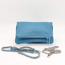 Cargar imagen en el visor de la galería, Bolso flap de piel lisa, doblado con doble cadena, una plateada y la otra con cinta de piel entre los eslabones. Puede llevarse de mano, o colgado con una cadena, con las dos, o dejar una colgando hacia abajo. Cierra con cremallera y, una vez doblado, con dos clips imantados. Una vez abierto el imán, lleva un bolsillo., de LaNievina. Vista con cadenas