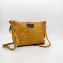 Cargar imagen en el visor de la galería, Bolso bandolera en piel vacuno, efecto escamas Cuadro pequeño de piel negra cosido como adorno en un de los frontales. Correa de 110 cm. ajustable, en piel del mismo color, con anillas y ganchos en latón envejecido. Interior forrado en tela color negro, con bolsillo cerrado con cremallera. De LaNievina. Color mostaza.