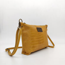 Cargar imagen en el visor de la galería, Bolso bandolera en piel vacuno, efecto escamas Cuadro pequeño de piel negra cosido como adorno en un de los frontales. Correa de 110 cm. ajustable, en piel del mismo color, con anillas y ganchos en latón envejecido. Interior forrado en tela color negro, con bolsillo cerrado con cremallera. De LaNievina. Color mostaza. Vista ladeada