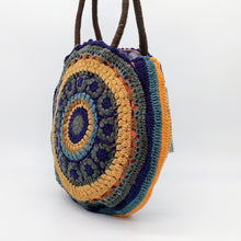 Cargar imagen en el visor de la galería, Bolso redondo de colores de crochet en lana acrílica. Dos asas cortas y otra larga de lana trenzada, de LaNievina. Vista lateral