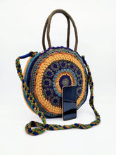 Cargar imagen en el visor de la galería, Bolso redondo de colores de crochet en lana acrílica. Dos asas cortas y otra larga de lana trenzada, de LaNievina. Colores azules y verdes, con movil para ver tamaño