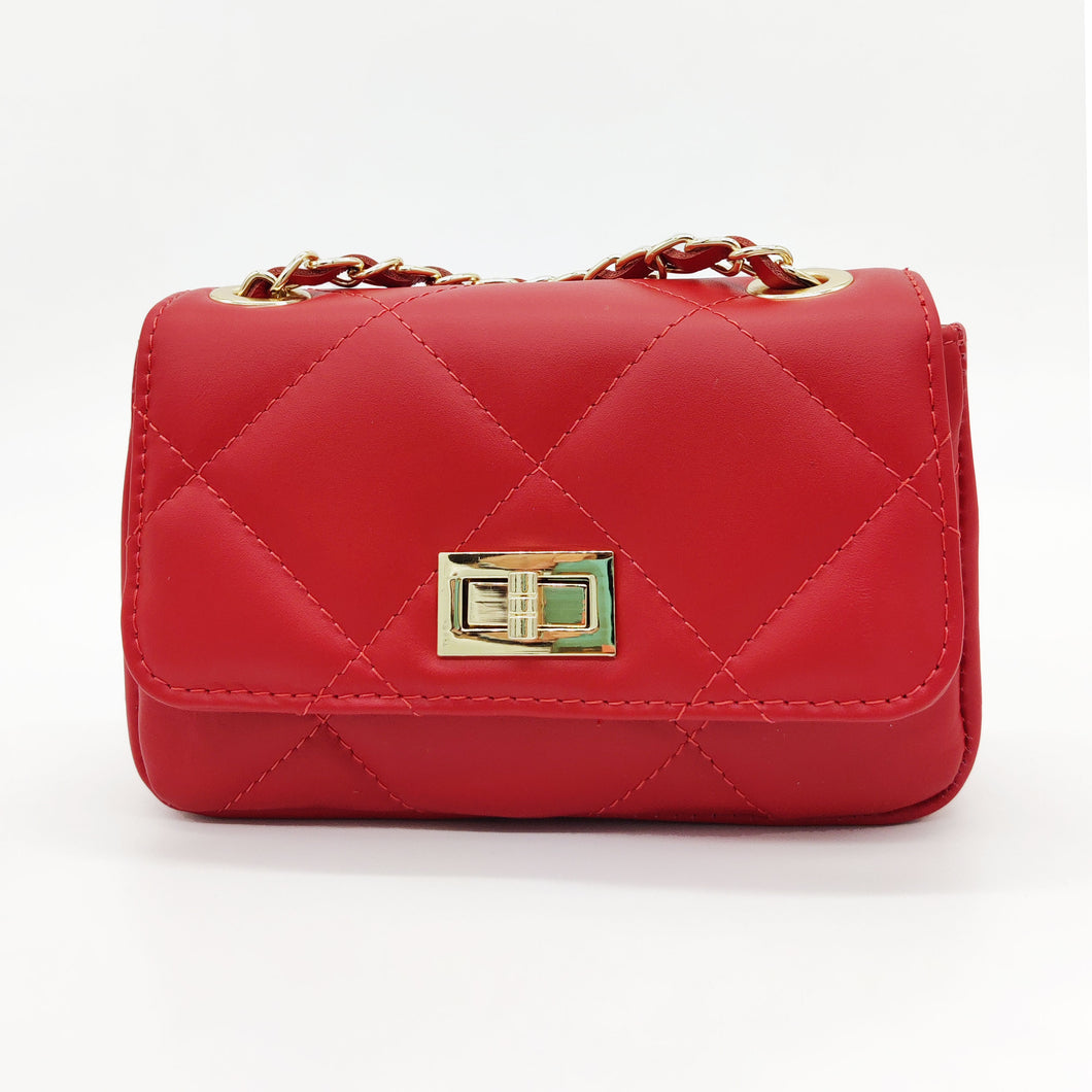 Bolso acolchado de piel en color rojo. Solapa con cierre giratorio metálico dorado. Asa larga de cadena dorada y piel. Interior forrado en tela, con bolsillo cerrado con cremallera. LaNievina.  Vista frontal