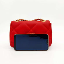Cargar imagen en el visor de la galería, Bolso de piel acolchado rombos, color rojo de LaNievina, contenido para ver tamañoBolso acolchado de piel en color rojo. Solapa con cierre giratorio metálico dorado. Asa larga de cadena dorada y piel. Interior forrado en tela, con bolsillo cerrado con cremallera. LaNievina. Vista con móvil para referencia de tamaño
