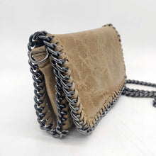 Cargar imagen en el visor de la galería, Bolso de piel de LaNievina, piel aspecto envejecido, con cadenas que adornan los bordes. Cierre clip y cremallera. Llevar cruzado o colgado al hombro, con asa larga de cadena. Color topo. Vista lateral
