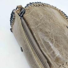 Cargar imagen en el visor de la galería, Bolso de piel de LaNievina, piel aspecto envejecido, con cadenas que adornan los bordes. Cierre clip y cremallera. Llevar cruzado o colgado al hombro, con asa larga de cadena. Color topo. Detalle del cierre con cremallera
