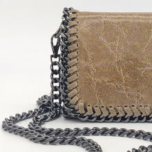 Cargar imagen en el visor de la galería, Bolso de piel de LaNievina, piel aspecto envejecido, con cadenas que adornan los bordes. Cierre clip y cremallera. Llevar cruzado o colgado al hombro, con asa larga de cadena. Color topo. Detalle piel y cadena
