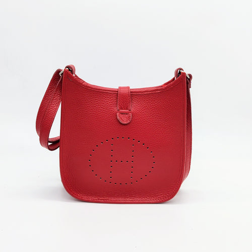 Bolso de piel color rojo. Puntitos taladrados en el frontal a modo de adorno. Cierra con una tira con clip imantado y cremallera. Asa larga para llevar al hombro. La Nievina. Vista frontal