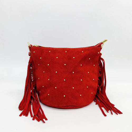 Bolso tipo hobo de ante color rojo de LaNievina, adornado con pepitas color dorado en el frontal y flecos de la misma piel en los lados. Fondo redondeado. Asa corta de piel, extraíble, para llevar en el hombro o en la mano. Asa larga de piel ajustable para llevar colgado. Cierra con cremallera. Interior forrado textil. Vista frontal.